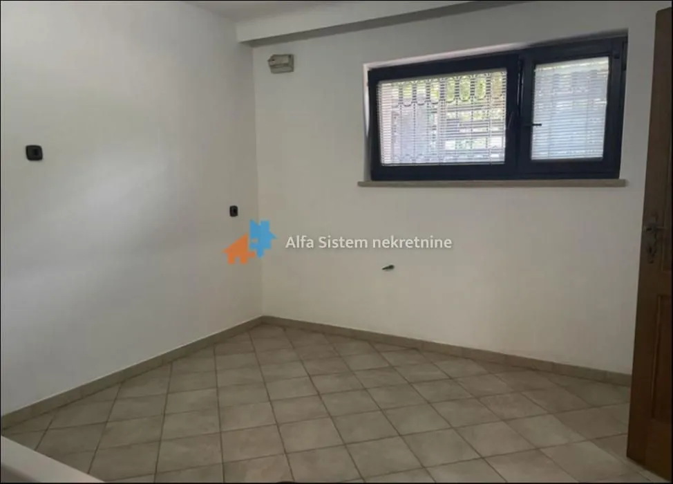 Empty room with ceramic floor tiles and a single window.
