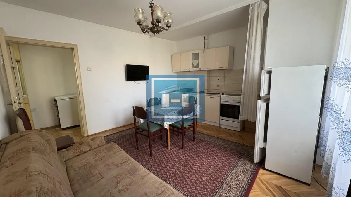 Dnevna soba sa trpezarijom i spojenom kuhinjom u pozadini.