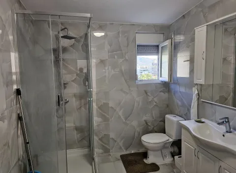 Bathroom equipped with a walk-in shower, washbasin, and toilet, featuring a window. - image 8
