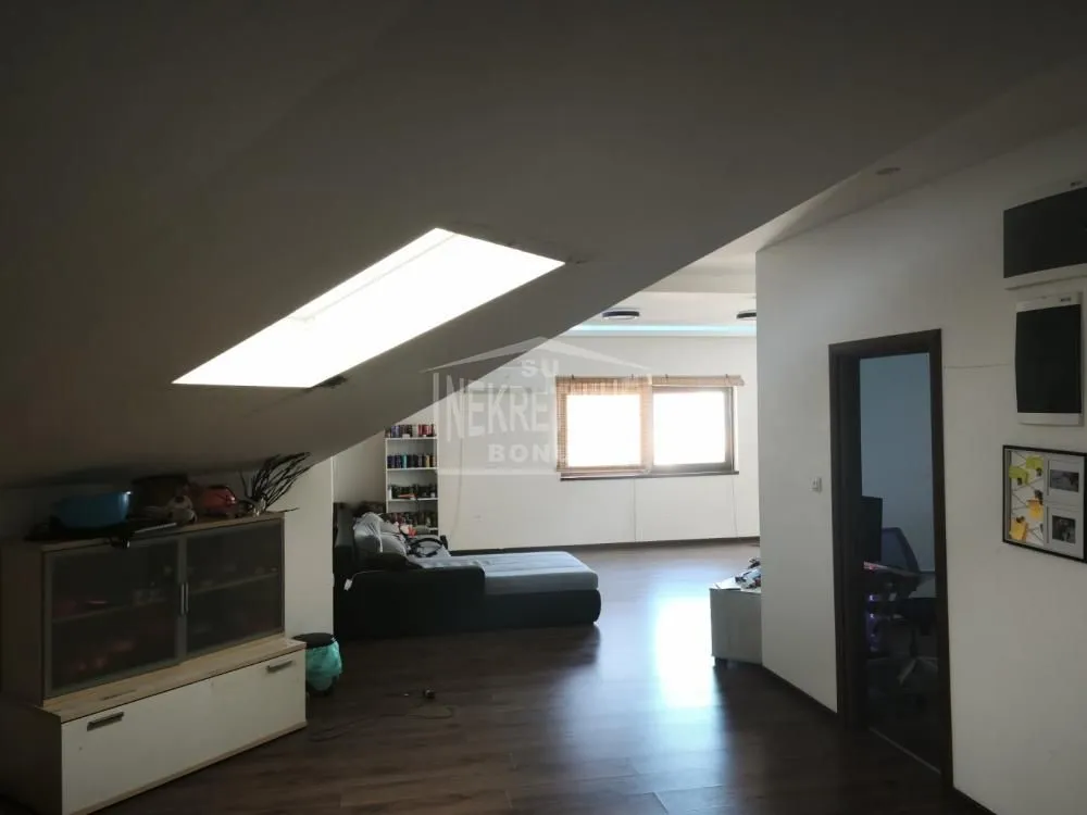 Dnevna soba u potkrovlju sa krovnim prozorom i nameštajem.