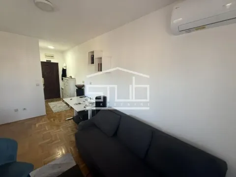 Living room with a sofa, desk, and air conditioning unit. - image 5