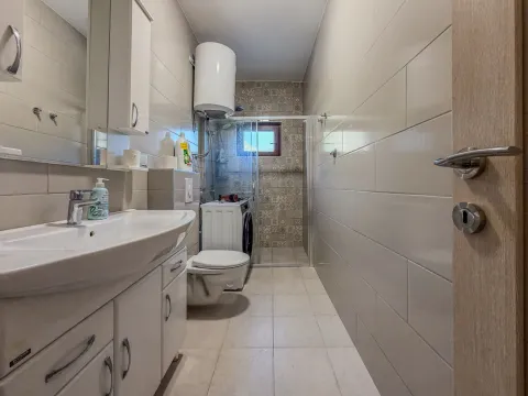 Kupatilo opremljeno umivaonikom, WC šoljom, tuš kabinom i mašinom za veš. - image 12