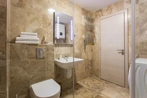 Modern tiled bathroom featuring a sink, toilet, and shower enclosure. - image 8