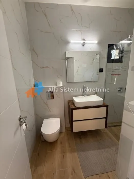 Savremeno opremljeno kupatilo sa umivaonikom, WC šoljom i tuš kabinom.