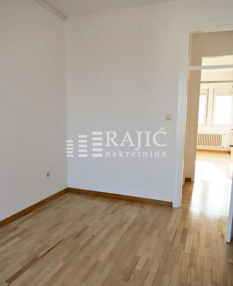 Empty room with hardwood floors and white walls.