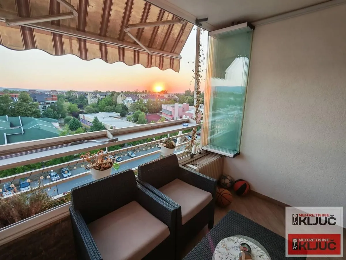 Namešten balkon sa garniturom za sedenje i pogledom na zalazak sunca.