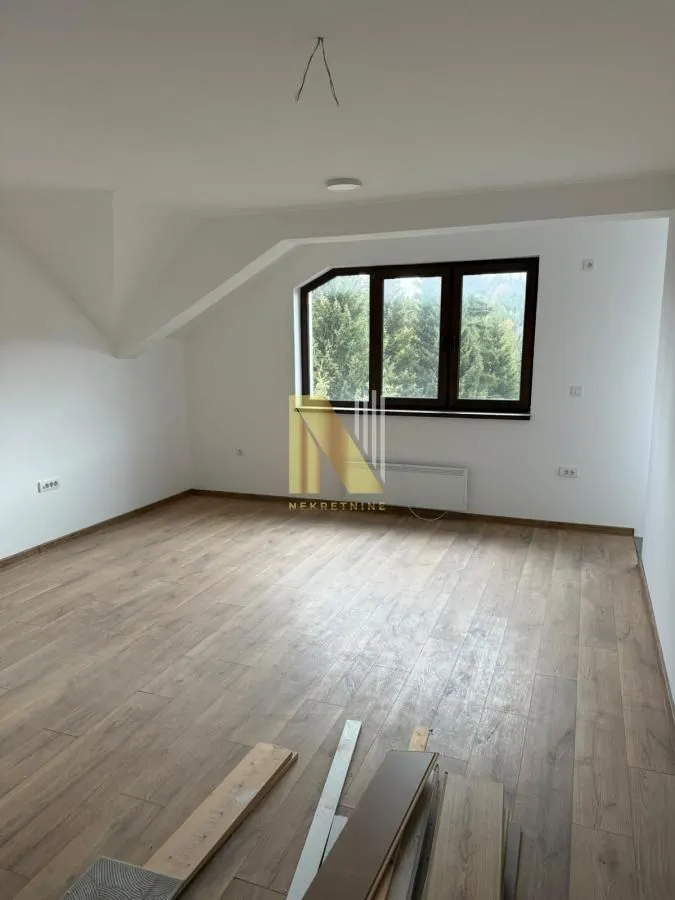 Empty room with laminate flooring and a window overlooking the forest.