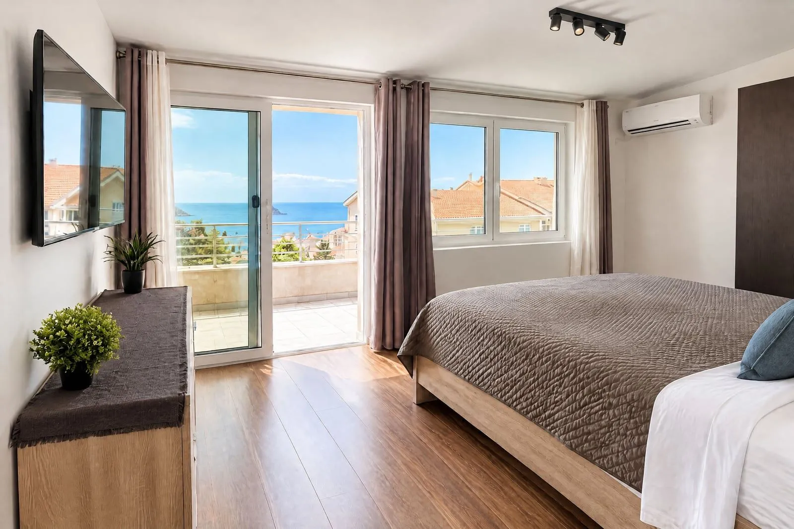 Bright bedroom with a double bed, TV, and access to a terrace with a sea view.