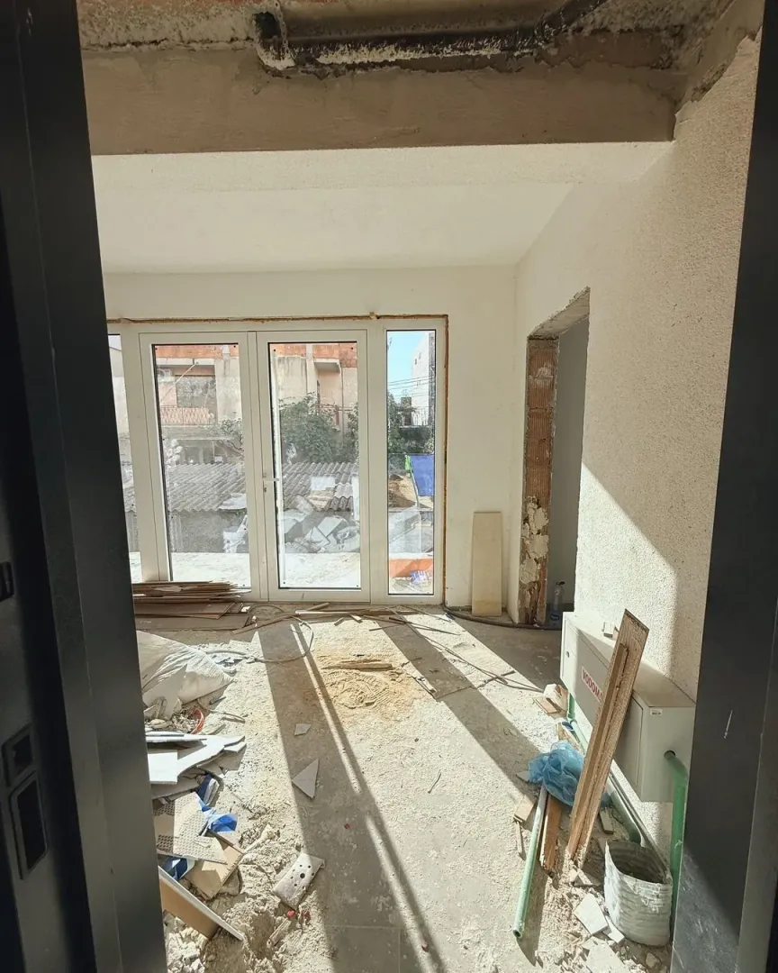 Room under construction with construction debris and a view through balcony doors.