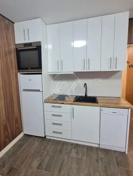 Small kitchen with white cabinets, built-in appliances and a wooden countertop. - image 12