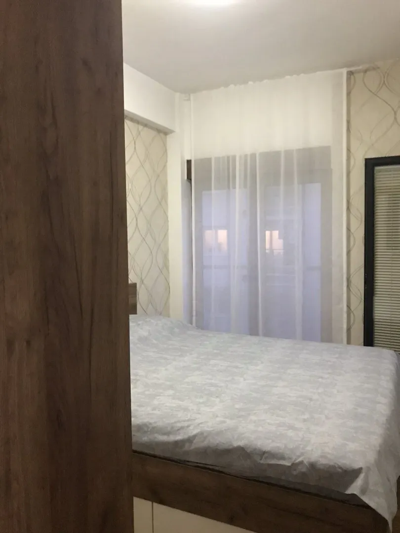 A bedroom with a double bed and a curtained window.