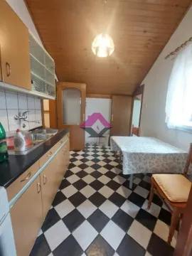 Kuhinja sa drvenim elementima, trpezarijskim stolom i kosim plafonom obloženim drvetom. - image 20
