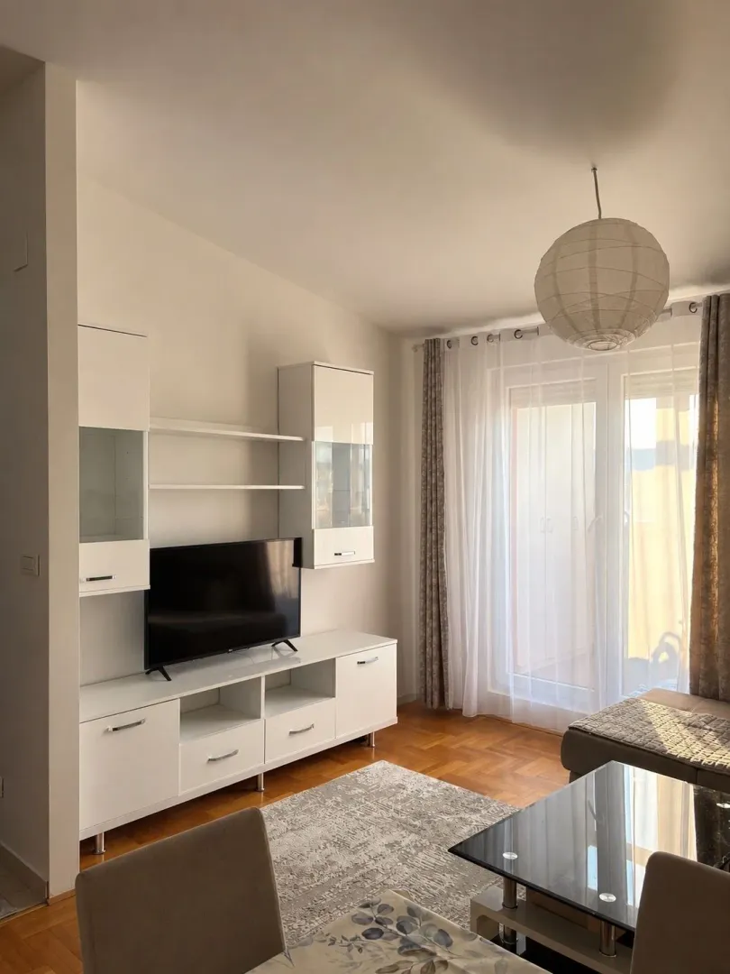 Svijetao dnevni boravak sa bijelim namještajom i trpezarijskim stolom.
