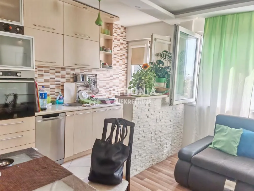 Kuhinja sa drvenim elementima i ugradnim aparatima.