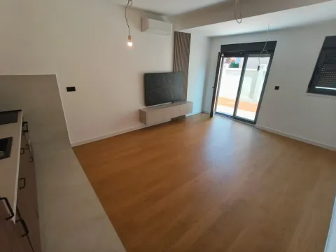 Prazan dnevni boravak sa drvenim podom, TV komodom i izlazom na terasu. - image 3
