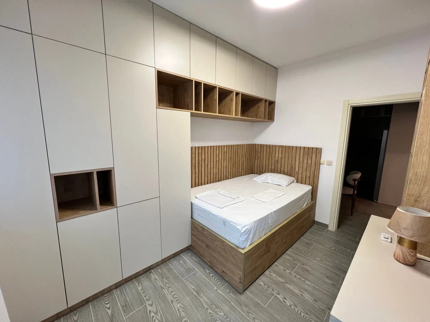 Modern bedroom with built-in wardrobe and wooden paneling.