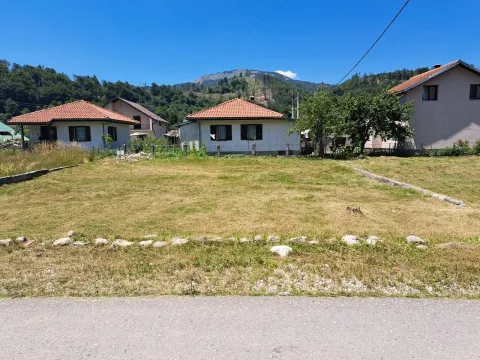 Travnati plac sa kućama u pozadini i pogledom na planinu. - image 3