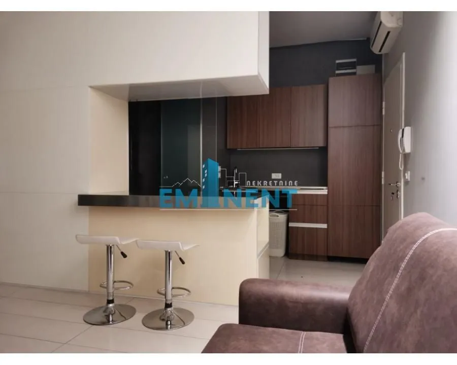 Small kitchen with a breakfast bar and bar stools connected to the living room.