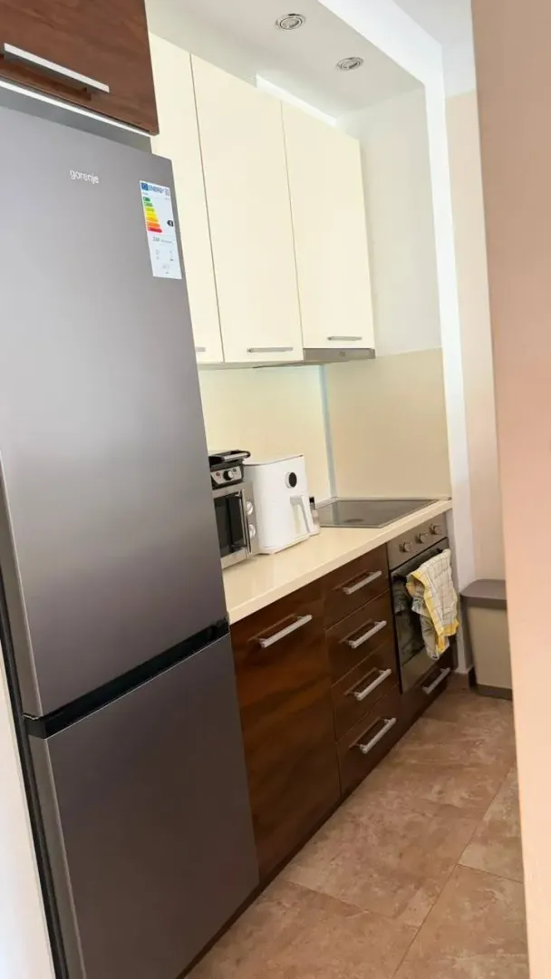 Small equipped kitchen with a refrigerator and wooden-tone cabinets.