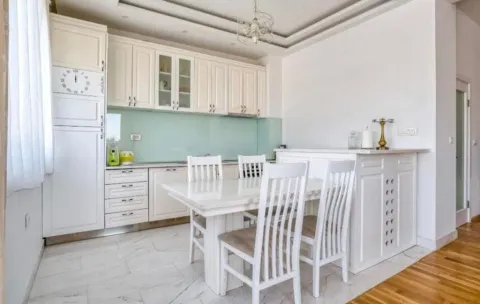 White kitchen with a dining table and white chairs. - image 6