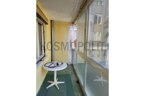 Zastakljeni balkon sa malim stolom i pogledom na okolne zgrade. - image 12