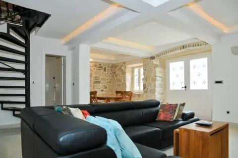 Dnevna soba sa crnom ugaonom garniturom, detaljima od kamena i stepeništem. - image 3