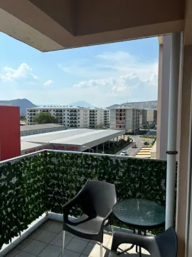 Small furnished balcony with a table and chairs and a view of surrounding buildings and hills. - image 9