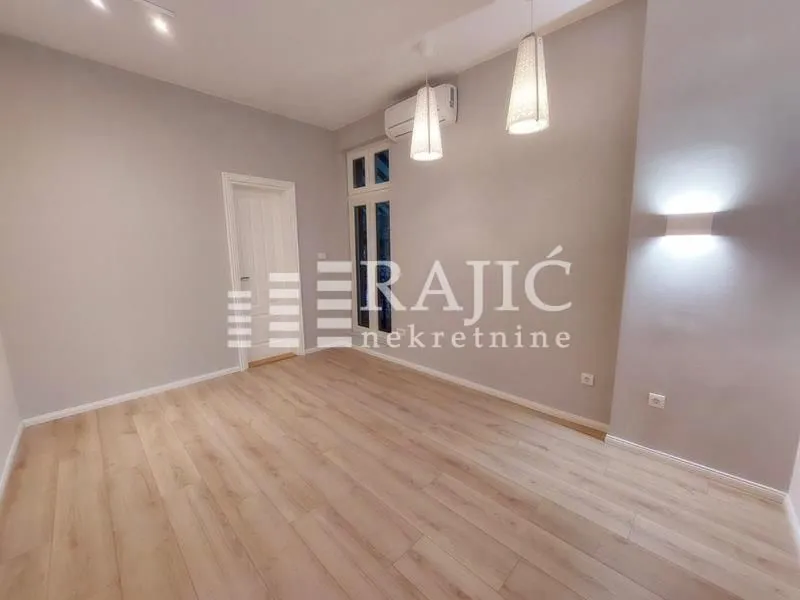 Empty room with laminate flooring and recessed lighting.