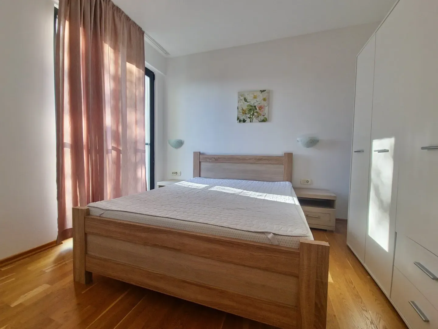 Bedroom with a double bed, white wardrobe, and wooden flooring.