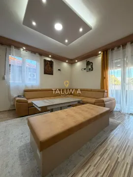 Living room with a sectional sofa, coffee table, and a drop ceiling with lighting. - image 19