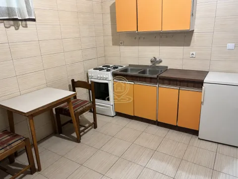 Manja kuhinja sa narandžastim elementima, šporetom i trpezarijskim stolom sa dve stolice. - image 5