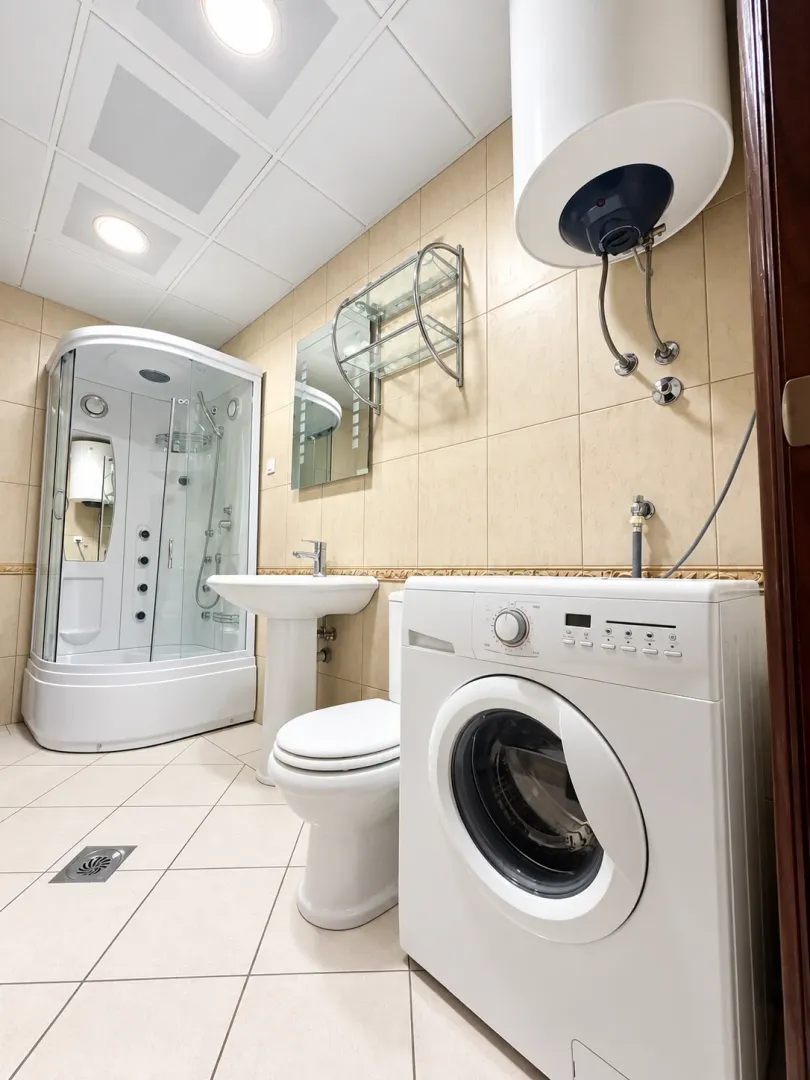 Bathroom equipped with a shower cabin, washbasin, toilet, and washing machine.