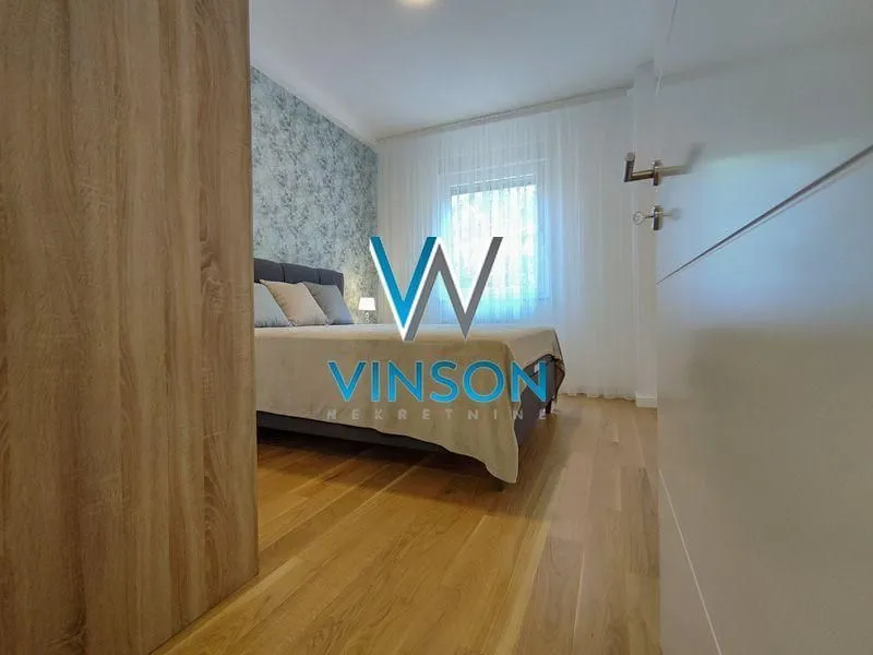 Pogled na spavaću sobu sa bračnim krevetom kroz otvorena vrata.