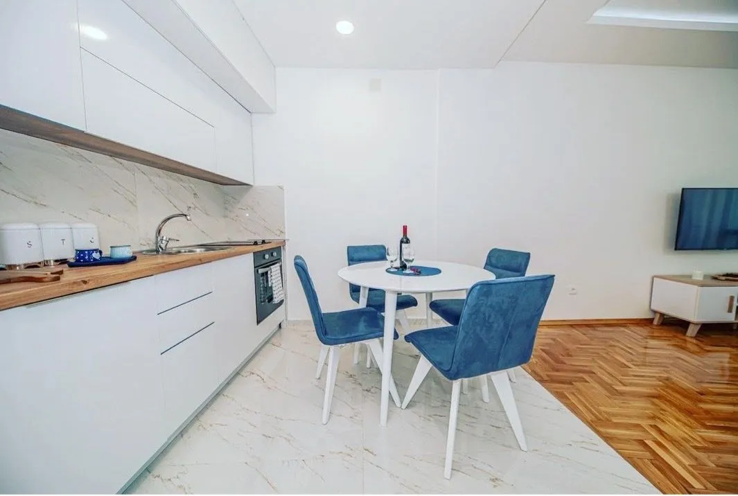Modern kitchen with white units and a dining table with blue chairs.