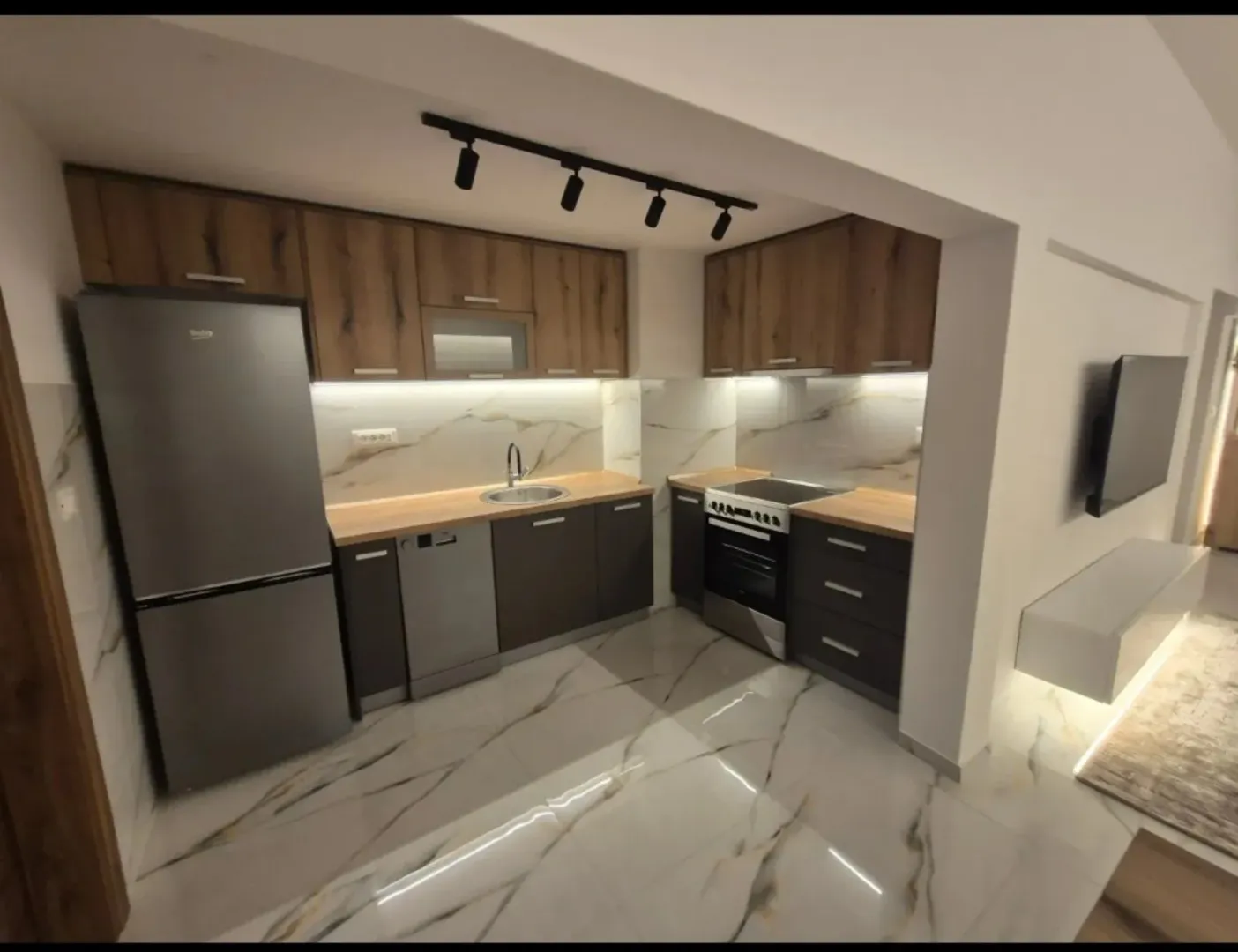Modern kitchen with built-in appliances and marble tiles.