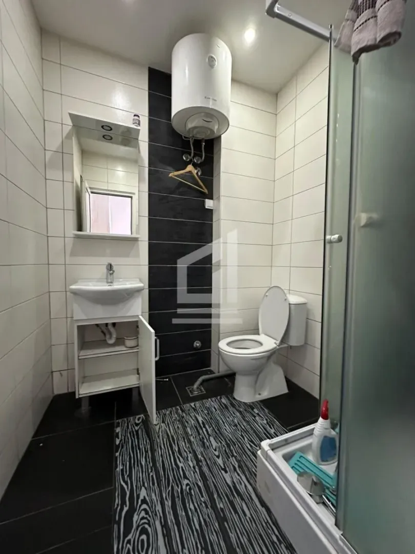 Bathroom with a sink, toilet, water heater and shower cabin.