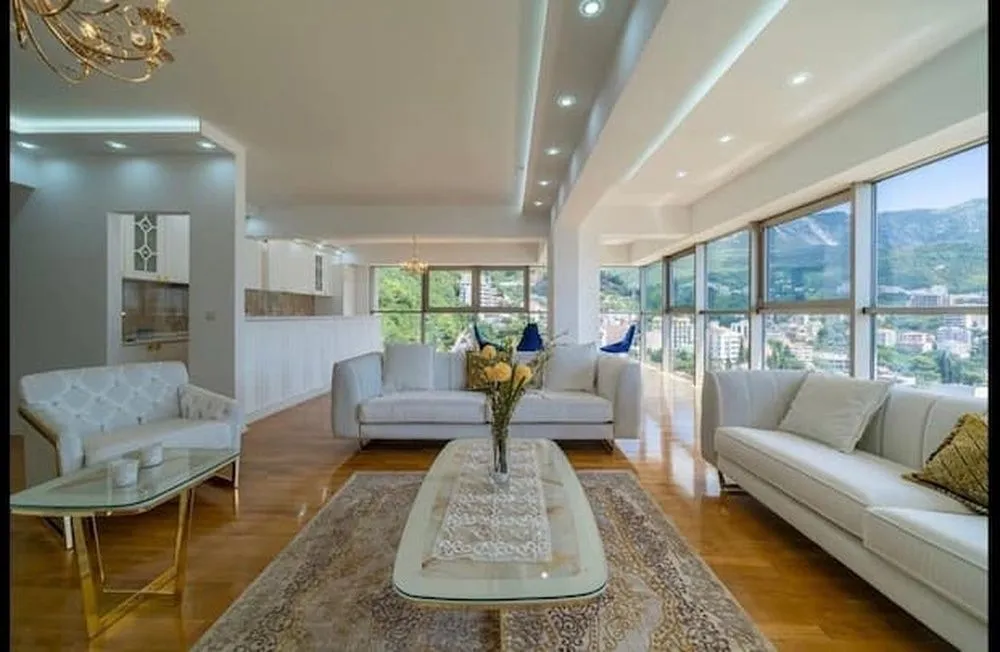 Spacious living room with white sofas and large glass surfaces with a view.