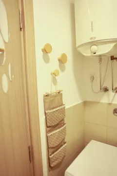 Bathroom detail featuring a water heater, wall hooks, and a hanging storage organizer. - image 20
