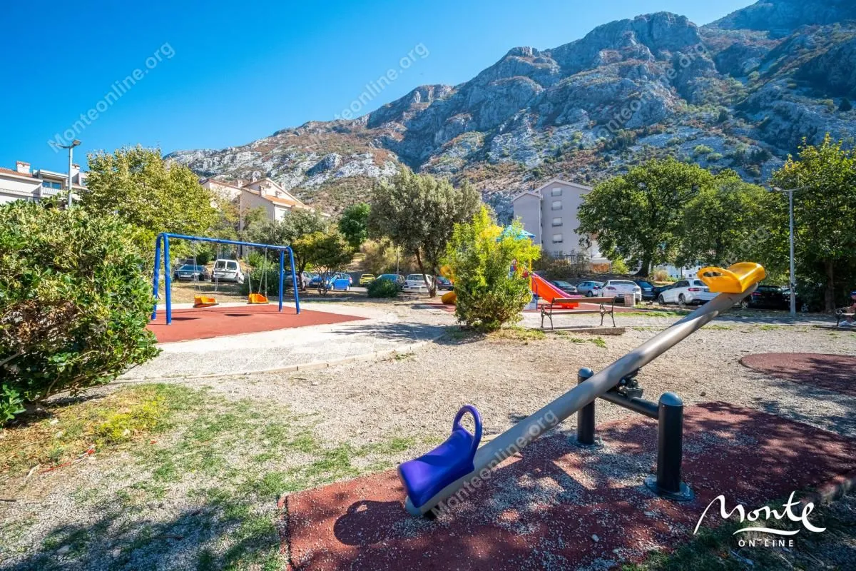 Dječije igralište sa ljuljaškama i klackalicama u okolini zgrade.