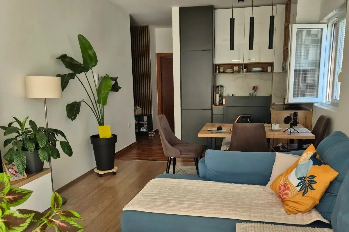 Modern living room with a sofa and an adjoining dining area.