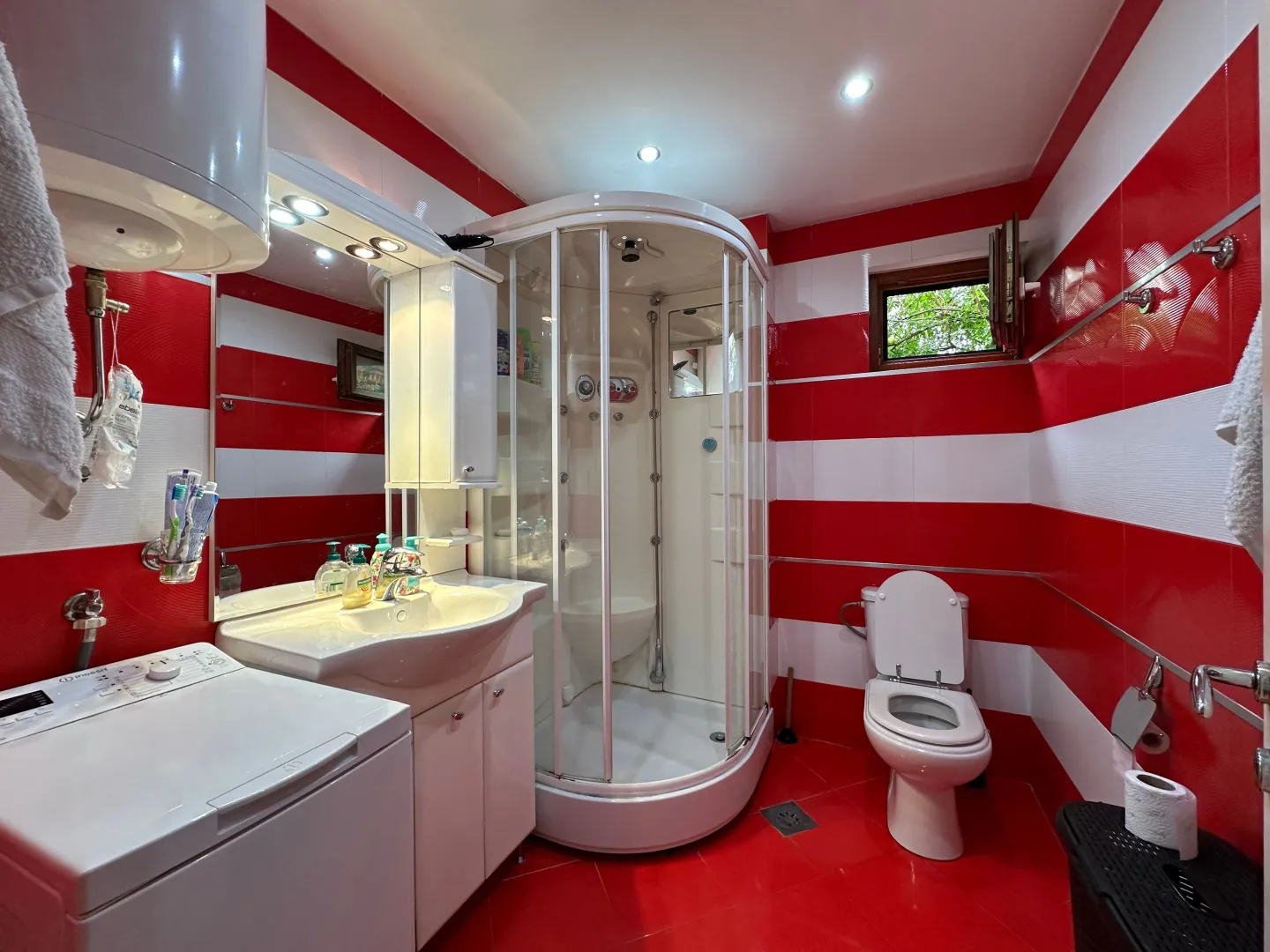 Bathroom with shower cabin, washbasin, toilet, and washing machine.