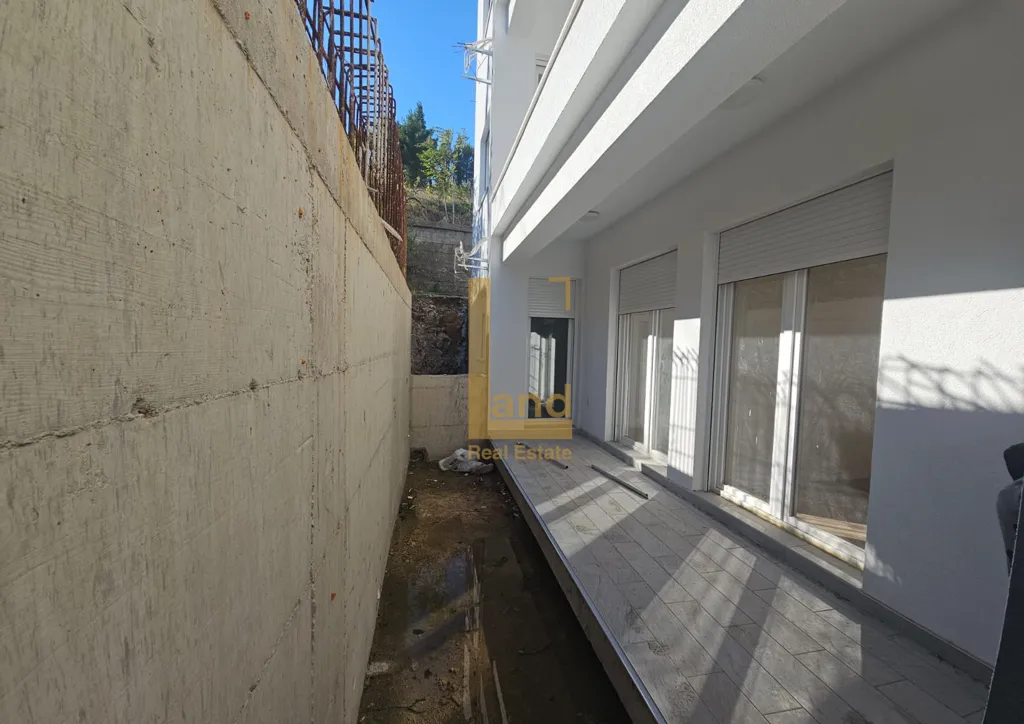 Eksterijer zgrade sa popločanim prolazom pored betonskog zida.