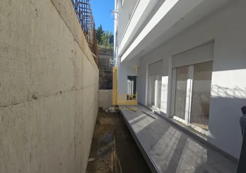 Eksterijer zgrade sa popločanim prolazom pored betonskog zida. - image 2