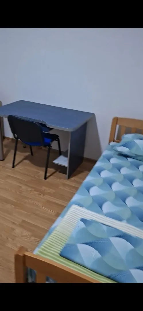 Manja spavaća soba sa krevetom i radnim stolom.