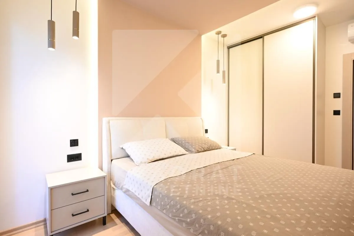 Modern bedroom with a double bed, nightstand, and fitted wardrobe.