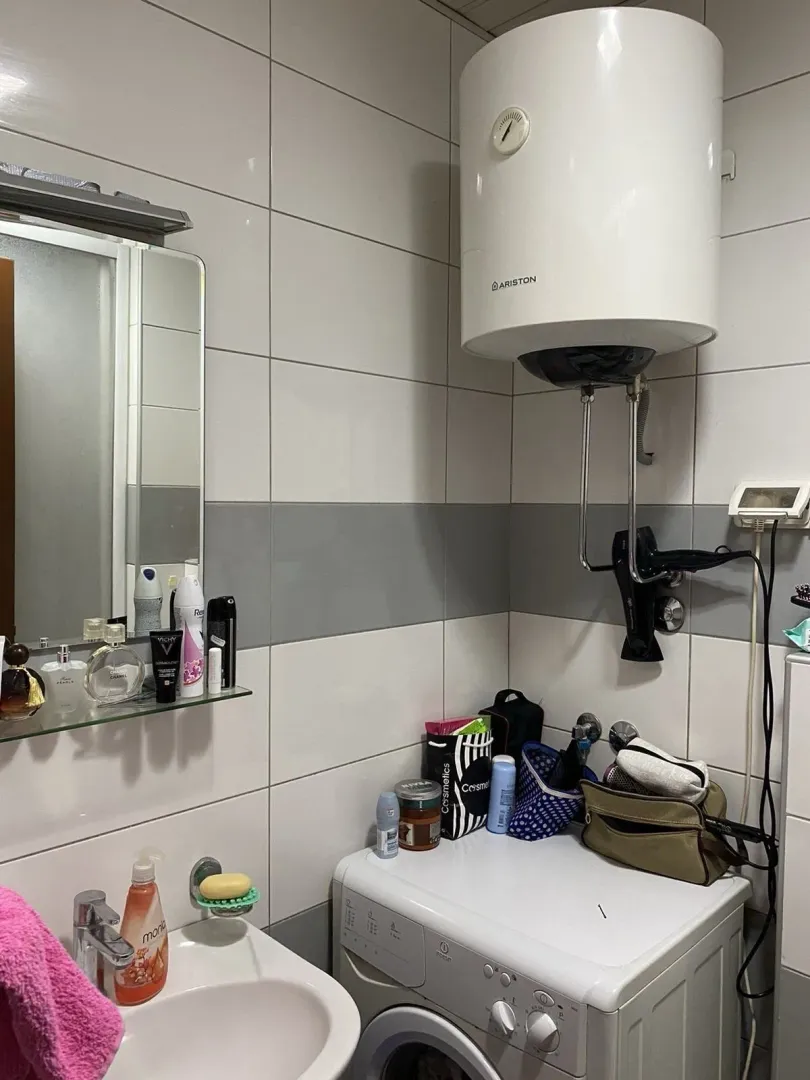 Part of a bathroom with a washing machine, mirror, and boiler.
