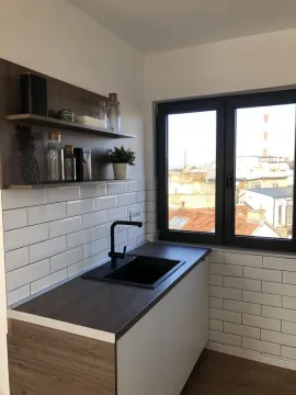 Part of the kitchen with a sink, countertop, open shelving, and a window with a city view. - image 13