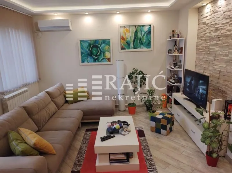 Furnished living room with a sectional sofa, TV, and decorative stone wall.