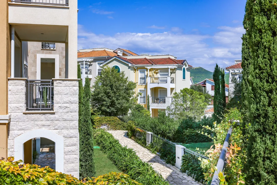 Pogled na spoljašnjost stambenog kompleksa sa uređenim dvorištem i stazama.