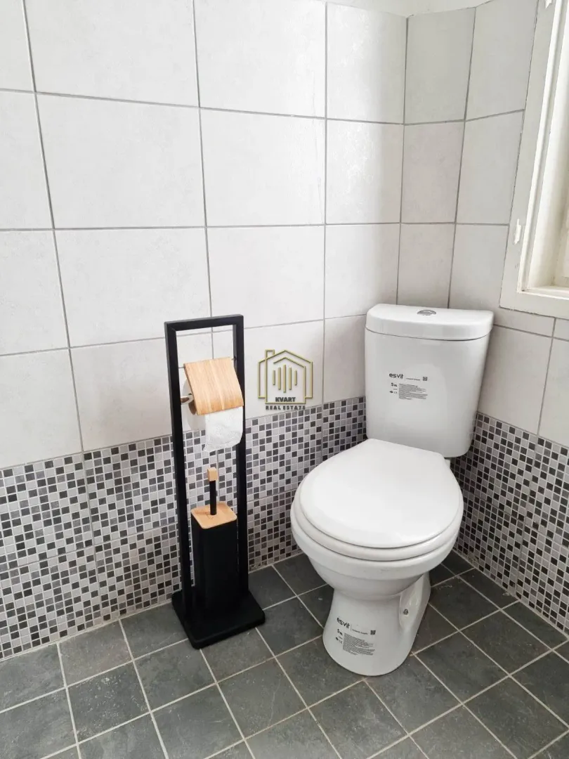 View of the bathroom with a toilet and a toilet paper holder.